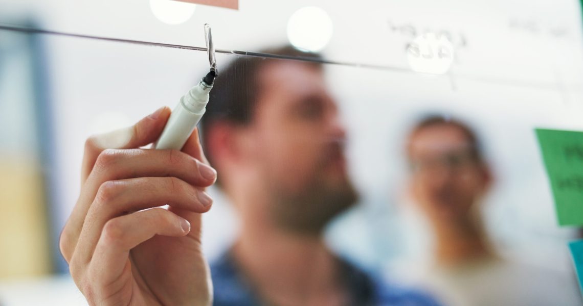 Shot of a group of designers brainstorming with notes on a glass wall in an office